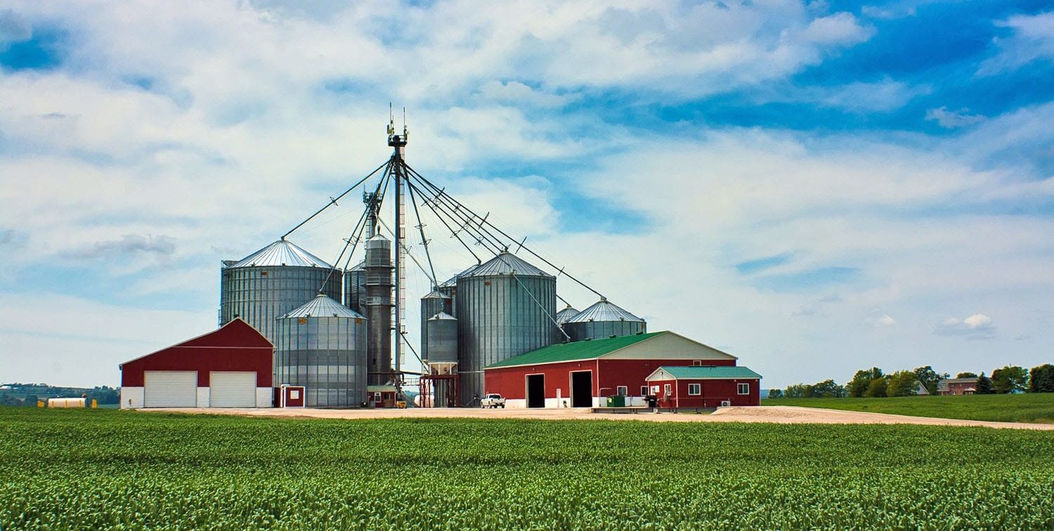 Red barns and grain bins on a clear day with a blue sky